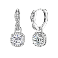 Sterling silver twisted hoop earrings with round moissanite stones in halo settings against neutral background.