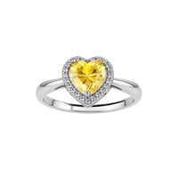 Heart-shaped yellow moissanite ring with diamond halo in sterling silver setting on neutral background