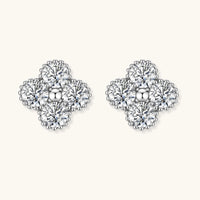 Dainty sterling silver quatrefoil stud earrings with four brilliant moissanite stones and center accent on white background.