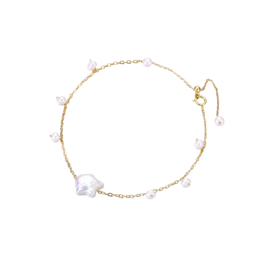 Delicate gold chain bracelet with baroque pearl centerpiece and small freshwater pearls on cream background.
