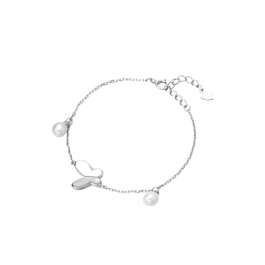 Delicate rhodium-plated silver chain bracelet with butterfly charm and two freshwater pearls on cream background