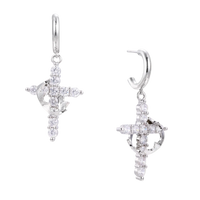 White gold-plated hoop earrings with sparkling zirconia cross charms dangling against cream background