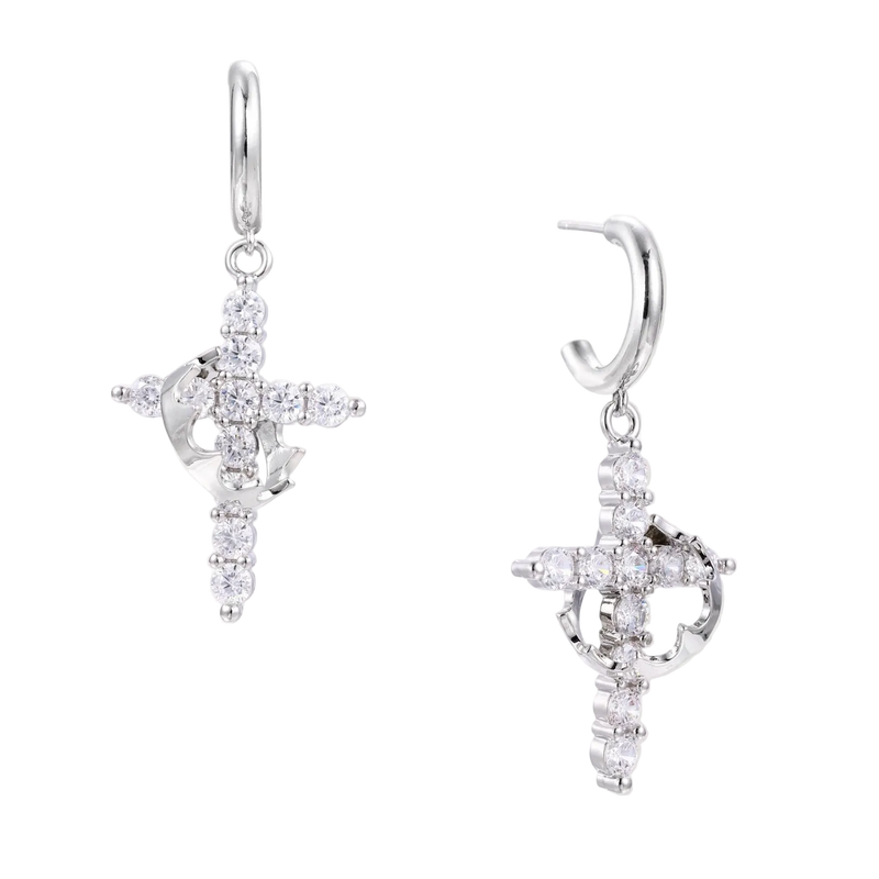 White gold-plated hoop earrings with sparkling zirconia cross charms dangling against cream background