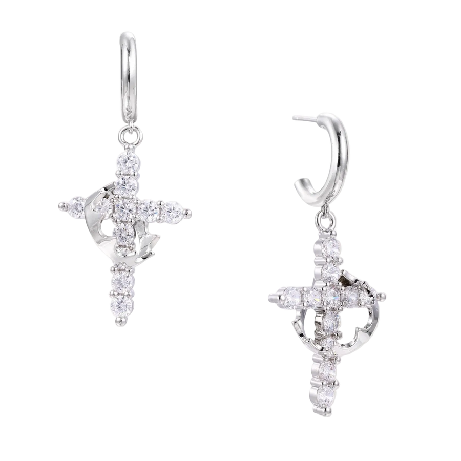 White gold-plated hoop earrings with sparkling zirconia cross charms dangling against cream background