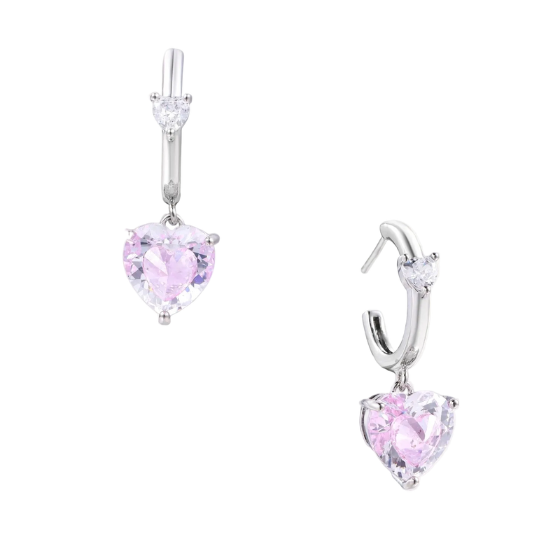 Silver huggie hoops with pink heart-cut zirconia pendants on white background, eco-friendly white gold plated brass