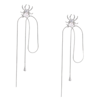 White gold plated spider earrings with pearl body and long threader chains on beige background