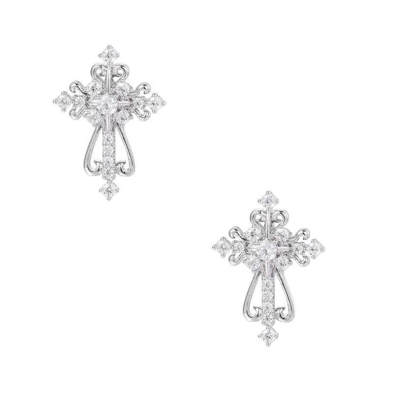 White gold-plated baroque cross studs with zirconia stones and ornate scrollwork on cream background.
