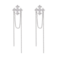 White gold plated baroque cross stud earrings with long cascading zirconia chains on cream background