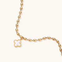 18K gold-plated oval bead bracelet with a four-leaf clover charm in mother-of-pearl or black enamel, adjustable lobster clasp, on white background.
