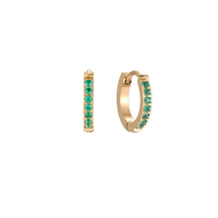 Pair of small gold huggie hoop earrings with bright green cubic zirconia stones on cream background