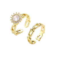 Two adjustable gold rings: chain-link band and halo-style ring with cubic zirconia stones on cream background
