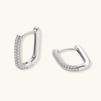 Close-up of platinum-plated sterling silver huggie hoops with pavé crystal setting on white background.