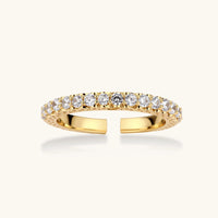Close-up of adjustable gold-plated ring with continuous row of round zirconia stones on neutral background.
