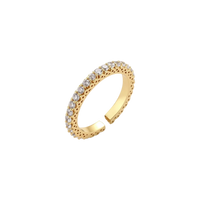 Close-up of adjustable gold-plated ring with continuous row of round zirconia stones on neutral background.