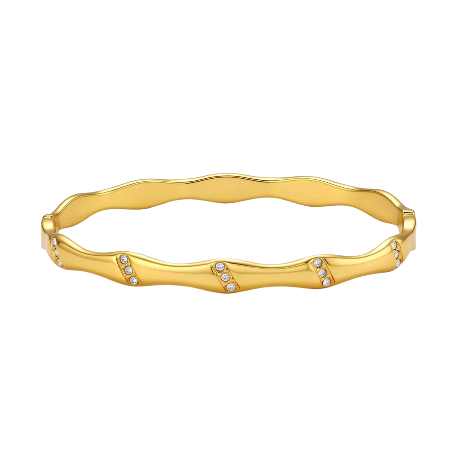 Gold-toned wavy bangle with bamboo-style segments and CZ crystal clusters on cream background. 18K plated stainless steel.