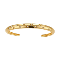 Polished 18K gold plated cuff bracelet with cubic zirconia set in star motifs on a cream background.