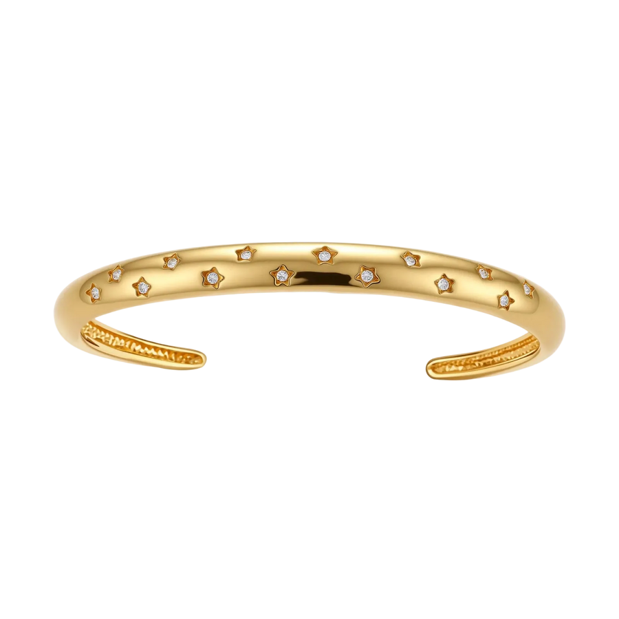 Polished 18K gold plated cuff bracelet with cubic zirconia set in star motifs on a cream background.