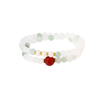 Three layered white beaded bracelets with carved orange agate lotus centerpiece and freshwater pearls on cream background.